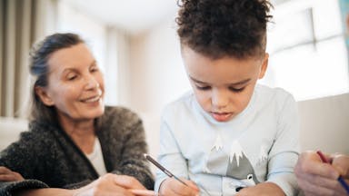 A grandmother and grandchild creating art, enriching family bonds in a cozy home setting.