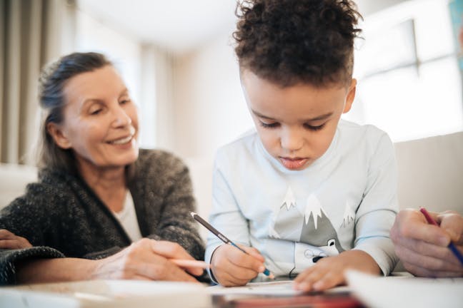 A grandmother and grandchild creating art, enriching family bonds in a cozy home setting.